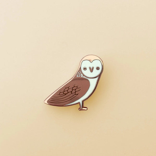 Owl-shaped pin on a beige background