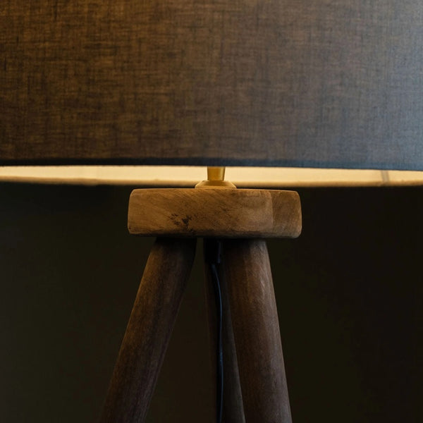 Close-up of a lamp with a wooden base and dark fabric shade against a dark background