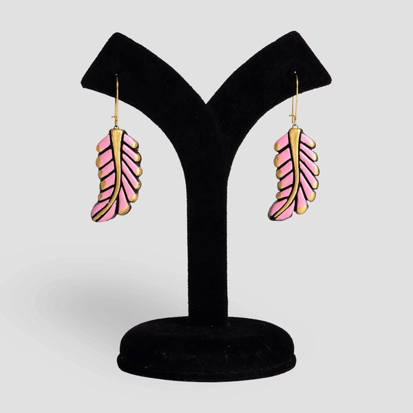 Pink feather-shaped earrings on a black velvet stand against a light gray background
