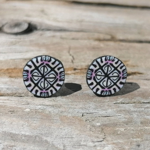 Pair of round earrings with black and white pattern on a wooden surface
