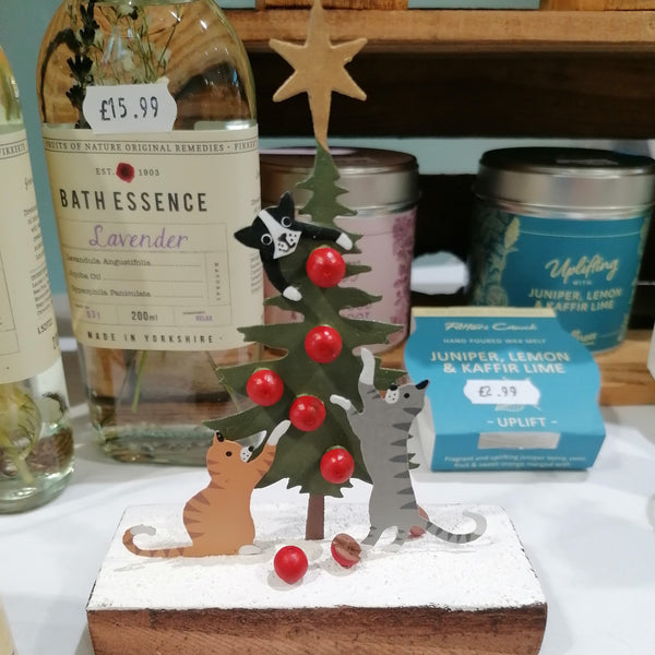 Decorative Christmas tree with animals on a shelf with various products in the background.