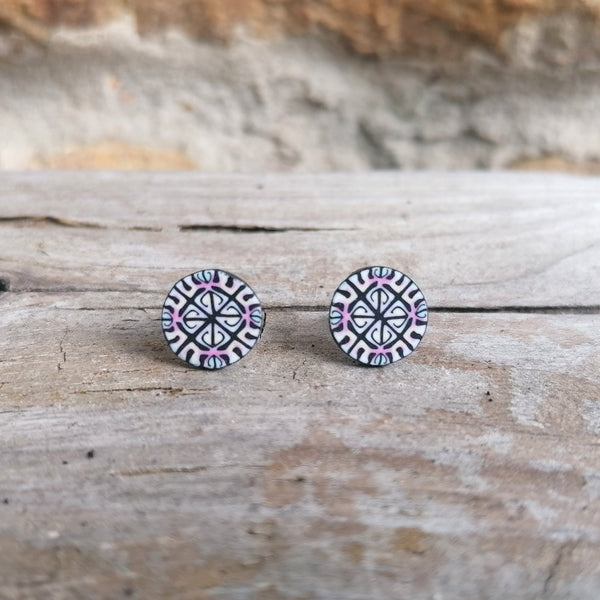 Pair of round earrings with a pattern on a wooden surface