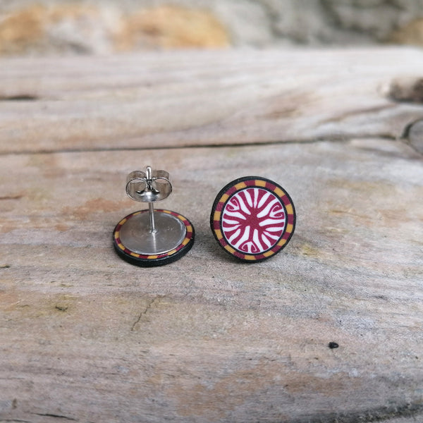 Pair of round earrings with a colorful design on a wooden surface