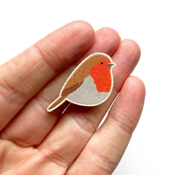 Wooden bird-shaped ornament held in a hand against a white background