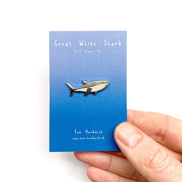 Great White Shark enamel pin on a blue card held by a hand