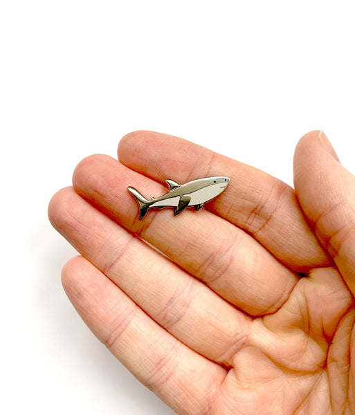 Small shark-shaped object held in a hand on a white background