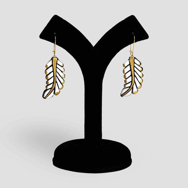 Feather-shaped earrings on a black stand against a light gray background