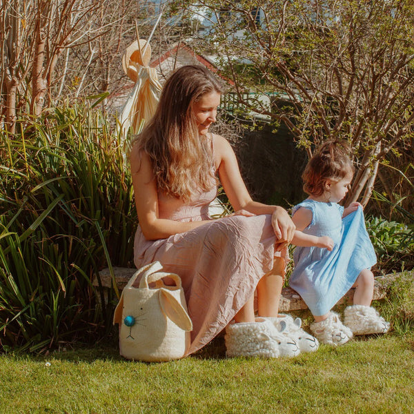 A woman and a child outside in the sunshine wearing handmade felted woolly sheep slippers by Sew Heart Felt